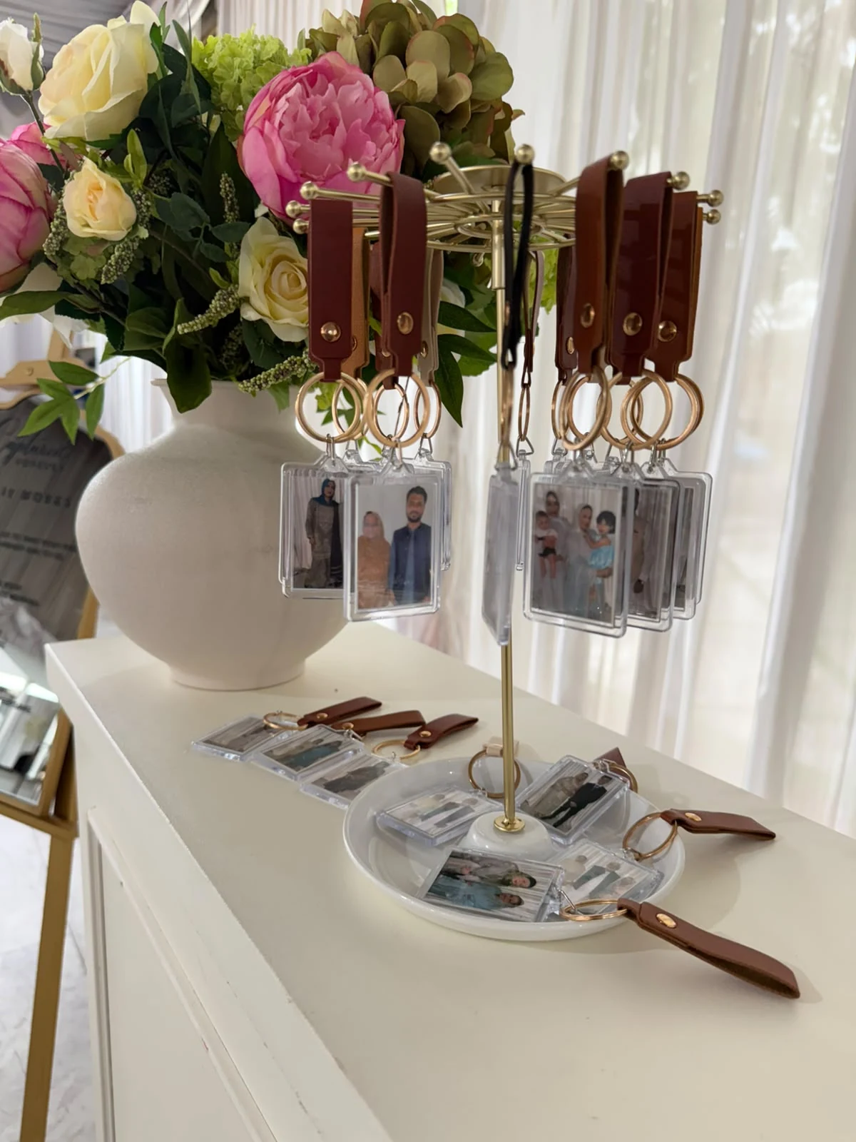 Finished personalised photo keyrings displayed on a brass stand beside a floral arrangement