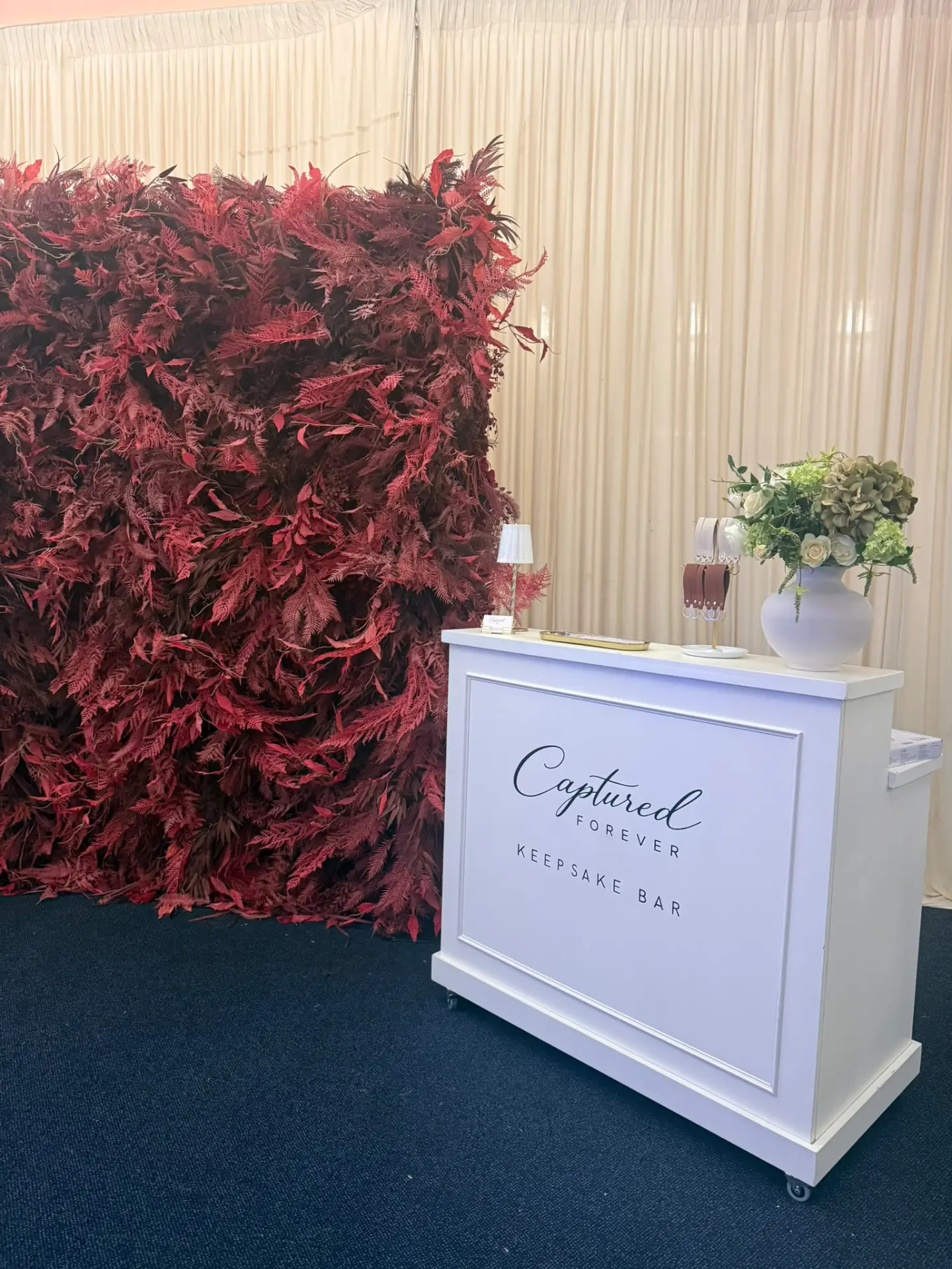 The Keepsake Bar beside a red floral wall in a draped marquee